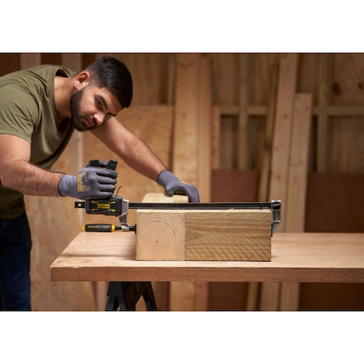 STANLEY® FATMAX® Hybrid Trigger Clamp, 450mm being used by a man to clamp two thick pieces of wood together in a workshop 
