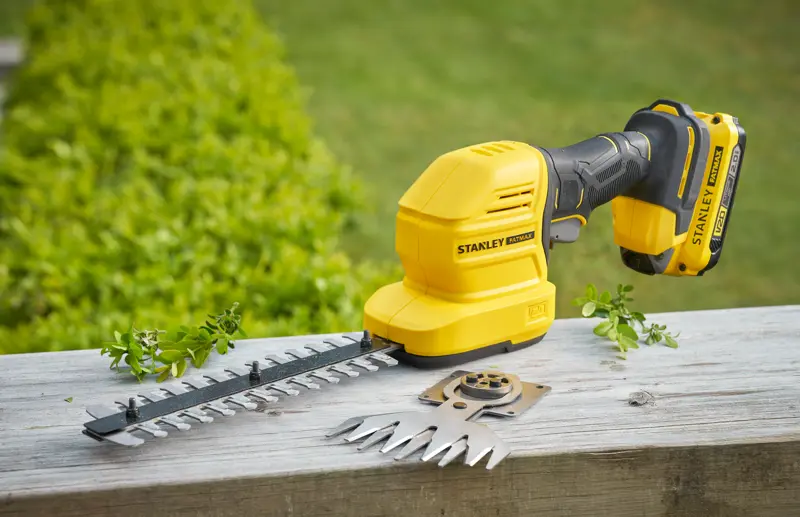 Photo du coupe-bordures et cisaille à arbustes sans fil STANLEY STCSS20B avec lames sur surface en bois.