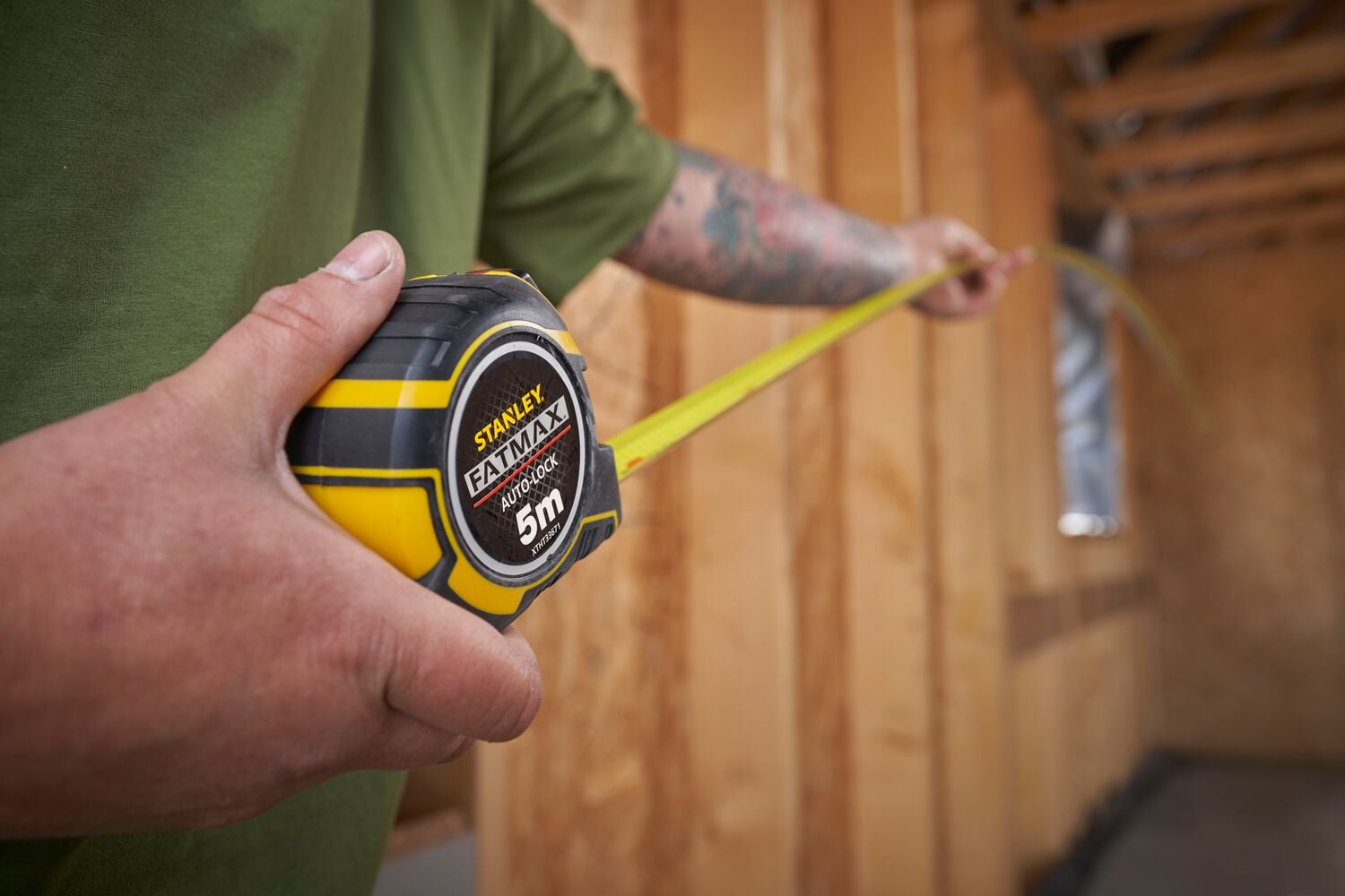 Photo du mètre ruban STANLEY XTHT0-33671 noir et jaune utilisé à l’intérieur d’une construction en bois.